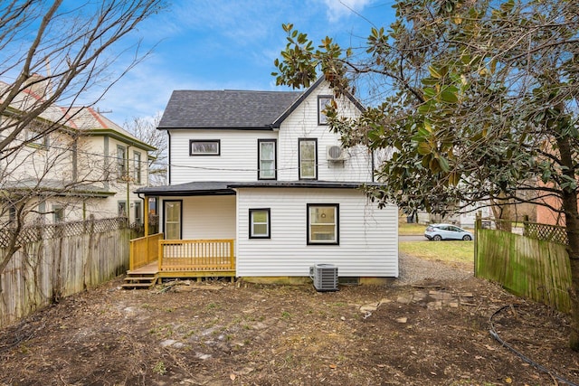 rear view of property with a deck, cooling unit, fence, and roof with shingles