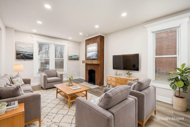 living room with a brick fireplace, recessed lighting, light wood-type flooring, and a wealth of natural light