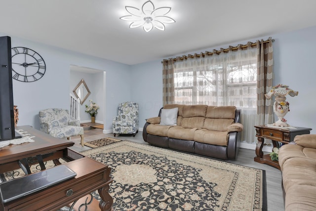 living area with baseboards, wood finished floors, and stairs