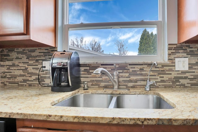 interior details with backsplash, light stone countertops, and a sink