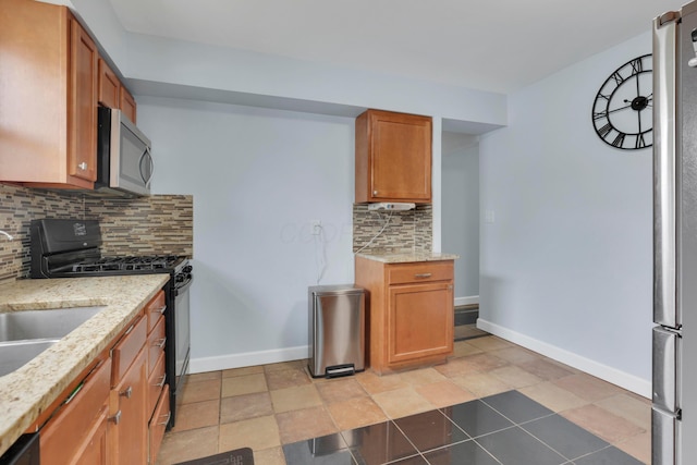 kitchen featuring baseboards, appliances with stainless steel finishes, and brown cabinets