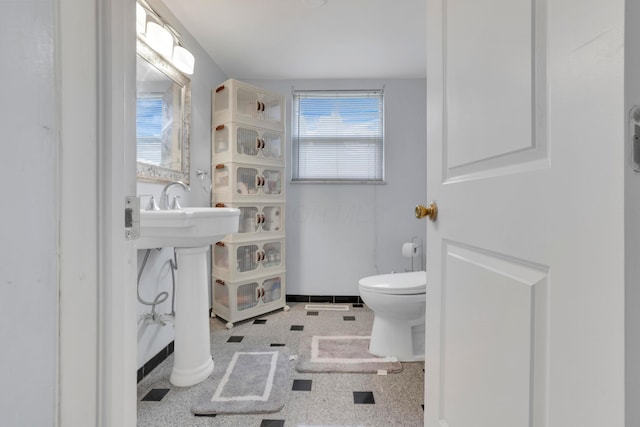 half bathroom featuring baseboards and toilet