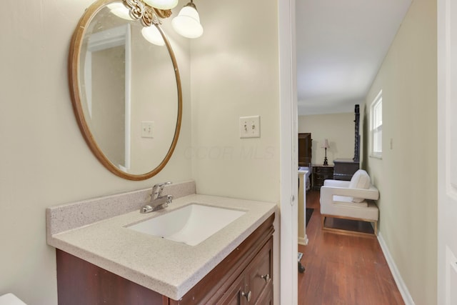 bathroom with vanity, a notable chandelier, wood finished floors, and baseboards