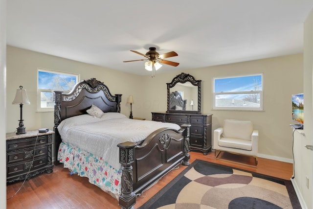 bedroom featuring multiple windows, dark wood-type flooring, baseboards, and ceiling fan