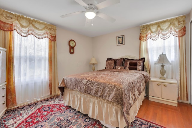 bedroom featuring multiple windows, light wood-style floors, and ceiling fan