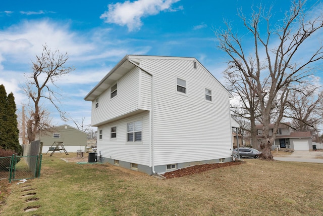 view of side of property with central air condition unit, a lawn, and fence