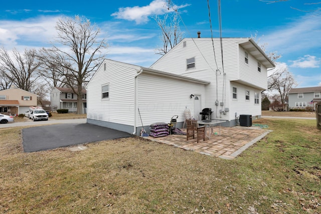 rear view of house with a lawn, central AC, and a patio