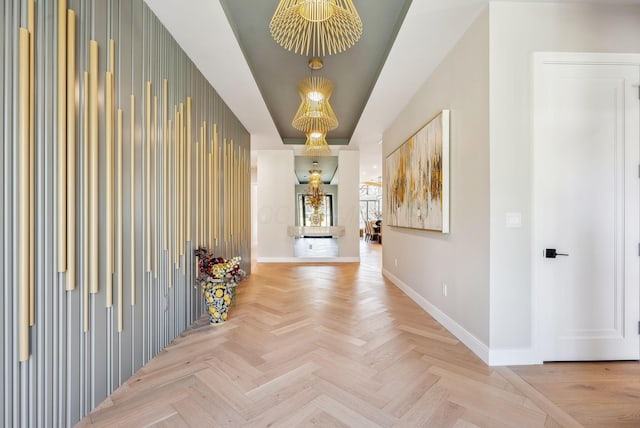 hallway with a tray ceiling and baseboards