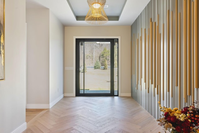 foyer entrance with a raised ceiling and baseboards