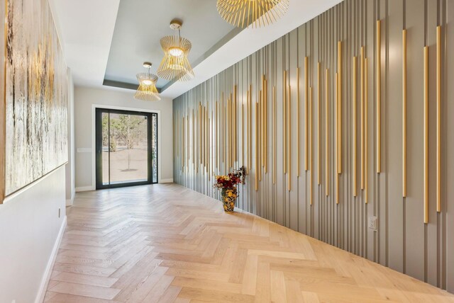 empty room with wood walls, a raised ceiling, and baseboards