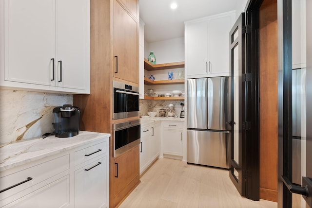 kitchen featuring light stone counters, decorative backsplash, white cabinets, stainless steel appliances, and a warming drawer