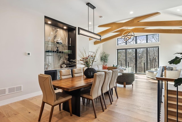 dining space featuring visible vents, light wood-style flooring, lofted ceiling with beams, and baseboards