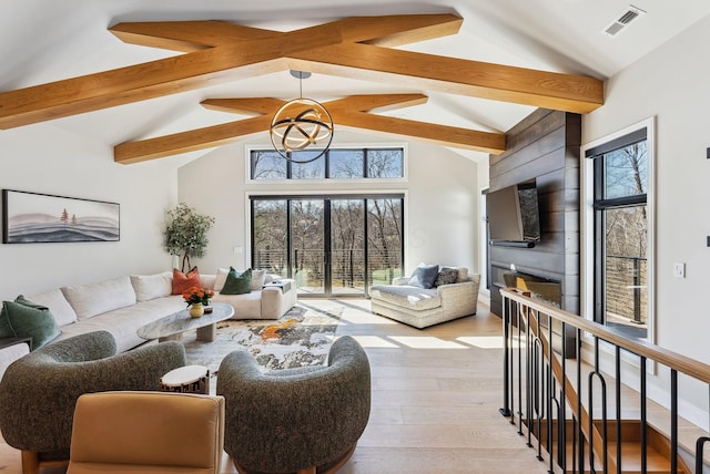 living room featuring visible vents, lofted ceiling with beams, a glass covered fireplace, and wood finished floors