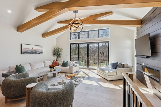 living area with beam ceiling, a glass covered fireplace, high vaulted ceiling, and wood finished floors