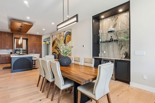 dining area with light wood-style flooring, recessed lighting, baseboards, and indoor bar