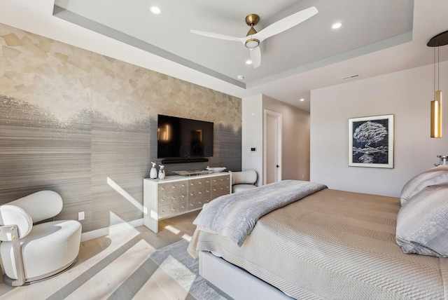 bedroom with an accent wall, a raised ceiling, and recessed lighting