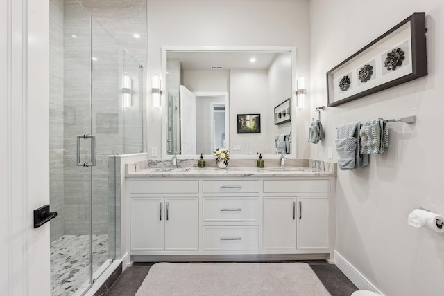 bathroom featuring a sink, baseboards, a stall shower, and double vanity