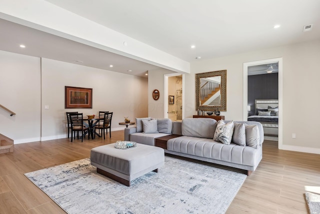 living area with recessed lighting, light wood-style flooring, and stairs