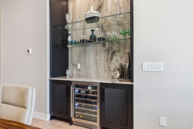 bar with baseboards, light wood-style floors, beverage cooler, and a dry bar