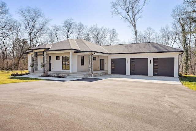 view of front of house with stucco siding, driveway, a shingled roof, and a garage