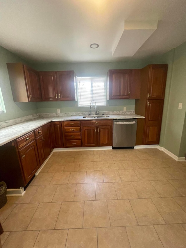 kitchen with a sink, light countertops, baseboards, and stainless steel dishwasher