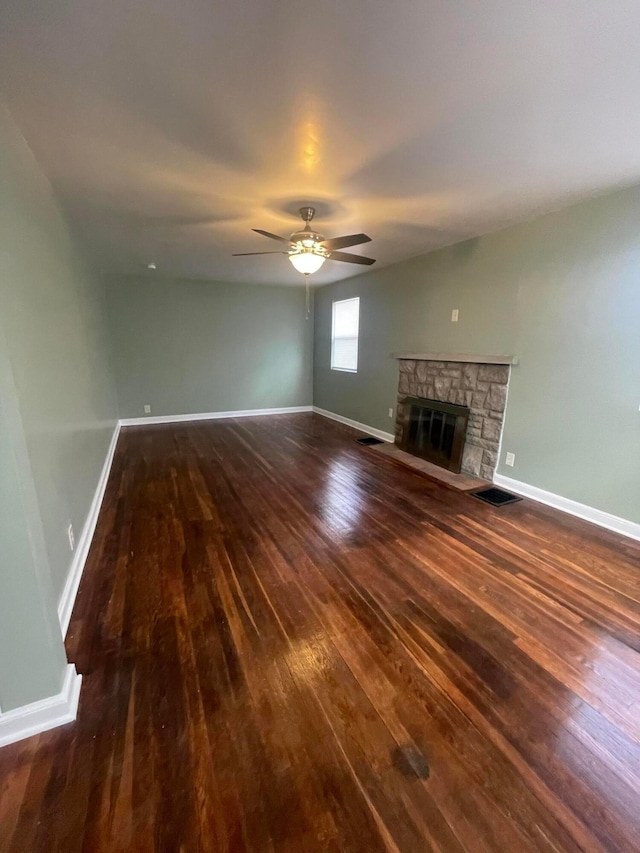 unfurnished living room with visible vents, ceiling fan, baseboards, a fireplace, and wood-type flooring