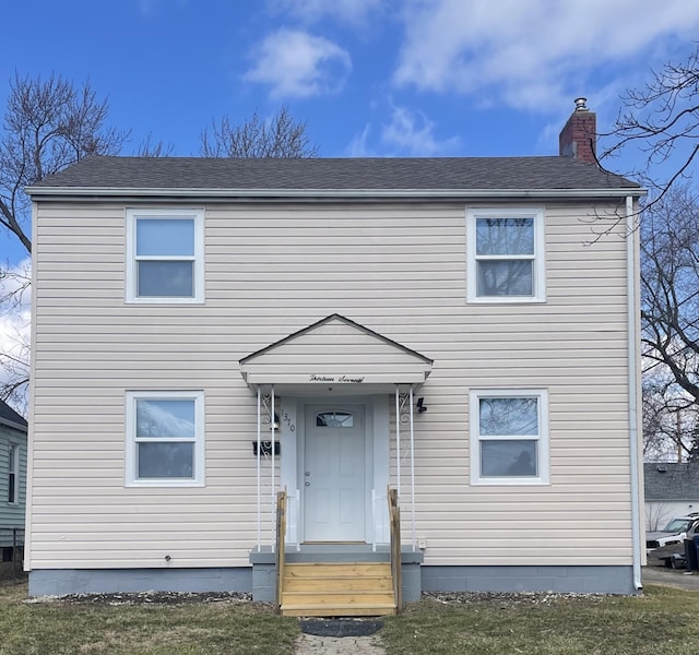 view of front of home with a shingled roof and a chimney