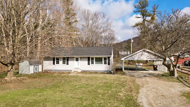 view of front of house with a front yard, fence, driveway, a shingled roof, and an outdoor structure