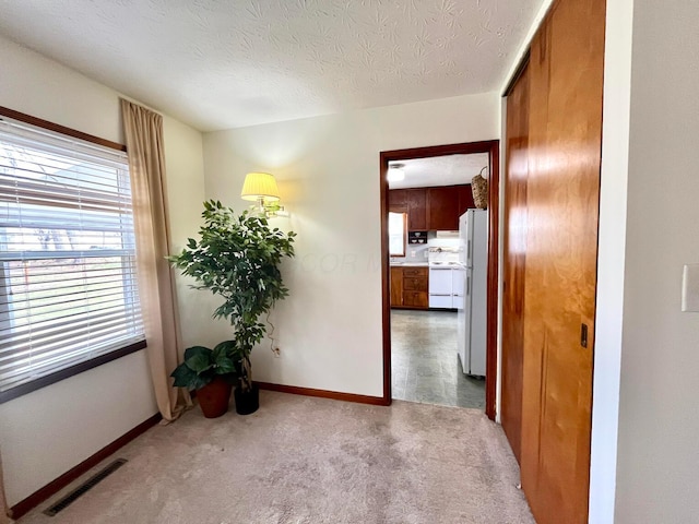 corridor featuring carpet flooring, baseboards, visible vents, and a textured ceiling