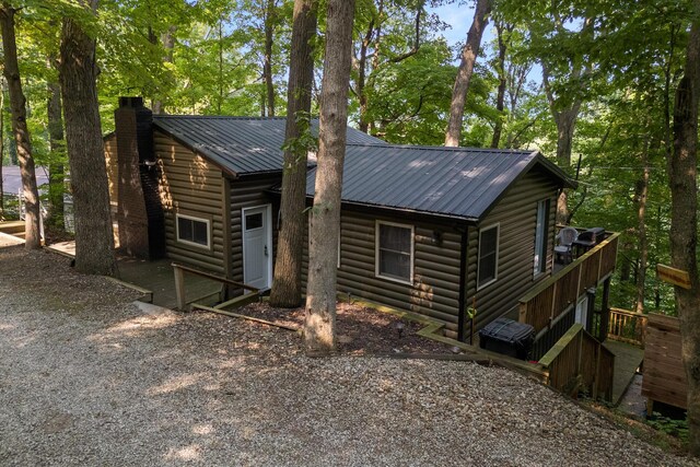 view of front of home featuring faux log siding, a chimney, and metal roof