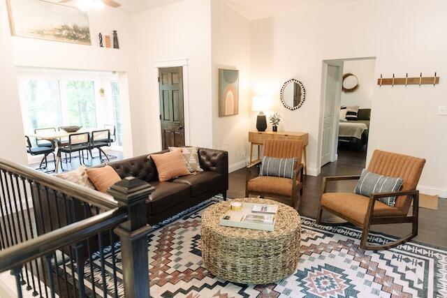 living area with wood finished floors, baseboards, a towering ceiling, and ceiling fan