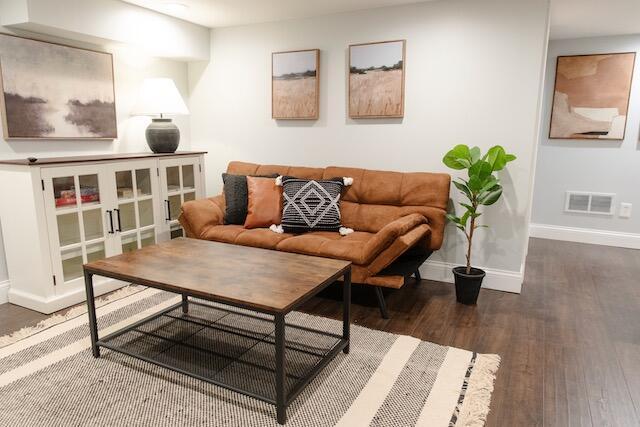 living room with visible vents, wood finished floors, and baseboards