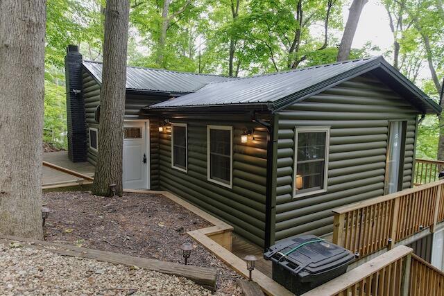 view of home's exterior with metal roof, a chimney, and faux log siding