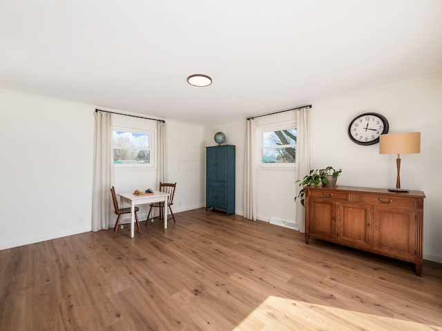 living area featuring a wealth of natural light, visible vents, baseboards, and light wood finished floors