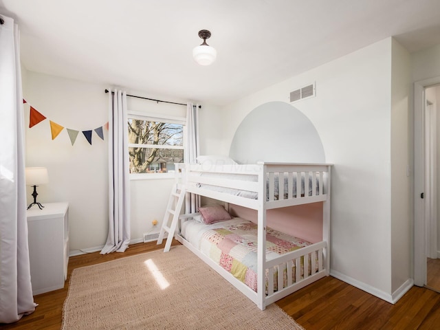 bedroom featuring wood finished floors, visible vents, and baseboards