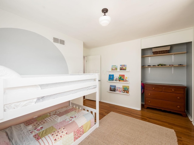 bedroom featuring visible vents, baseboards, and wood finished floors