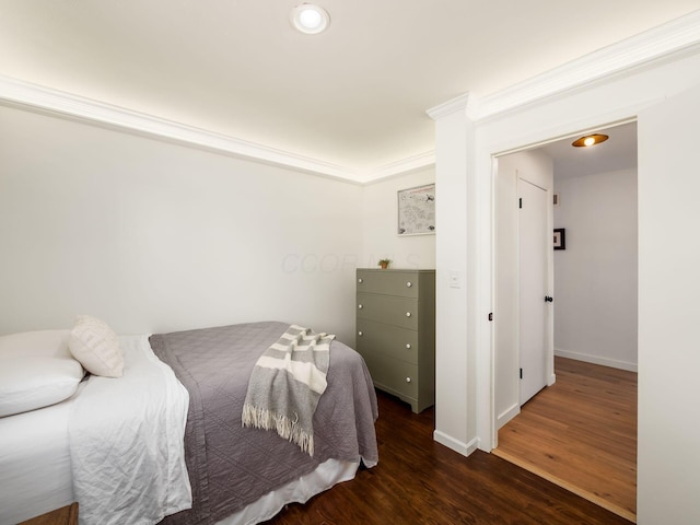 bedroom featuring wood finished floors, baseboards, and ornamental molding