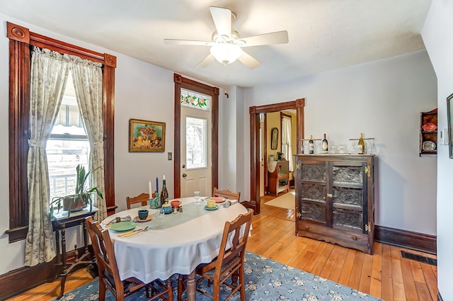 dining space featuring baseboards, hardwood / wood-style floors, and a ceiling fan