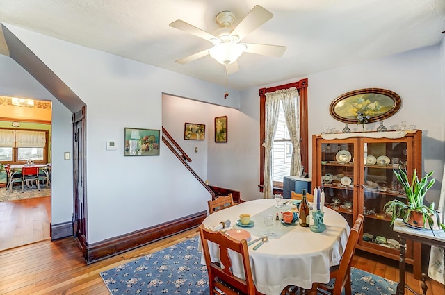 dining area with baseboards, light wood finished floors, and ceiling fan