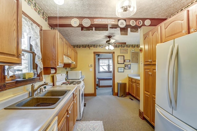 kitchen featuring white appliances, baseboards, a sink, light countertops, and under cabinet range hood