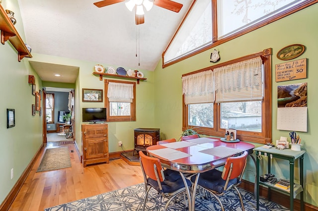 dining room featuring a ceiling fan, baseboards, light wood finished floors, vaulted ceiling, and a textured ceiling