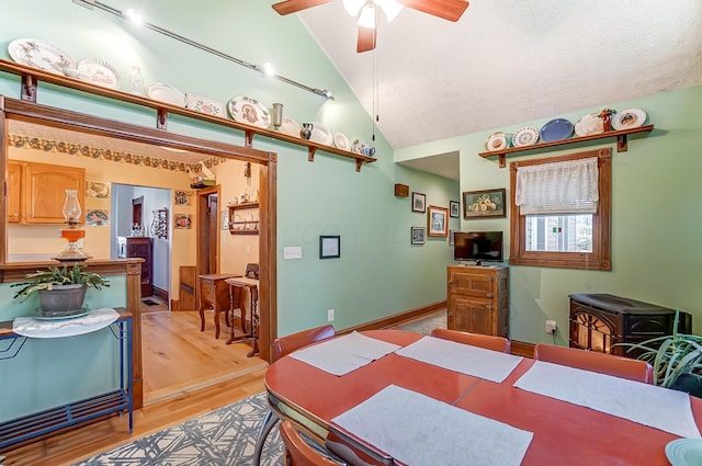 dining area featuring lofted ceiling, a ceiling fan, a textured ceiling, light wood-style floors, and baseboards