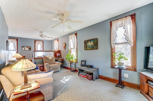 carpeted living room featuring baseboards, a textured ceiling, and a ceiling fan