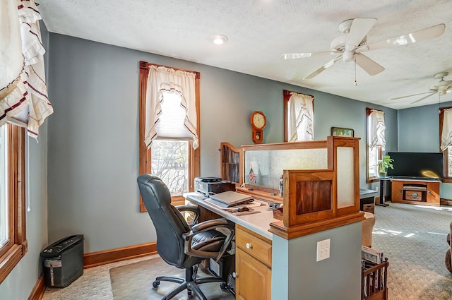 carpeted home office with ceiling fan, baseboards, and a textured ceiling