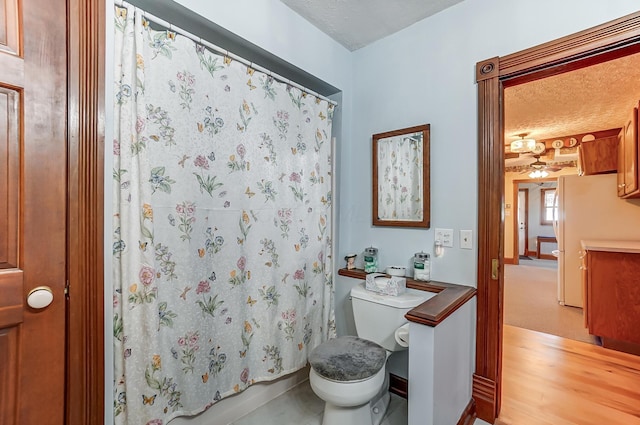 bathroom featuring a textured ceiling, toilet, and wood finished floors