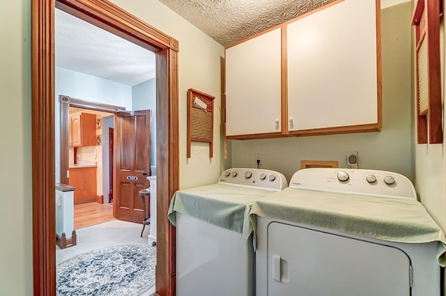 washroom with cabinet space, washing machine and dryer, and a textured ceiling