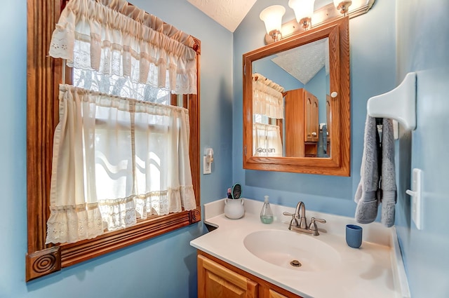 bathroom with a wealth of natural light, lofted ceiling, a textured ceiling, and vanity