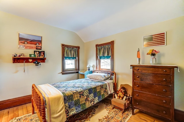 bedroom with hardwood / wood-style floors, vaulted ceiling, and baseboards