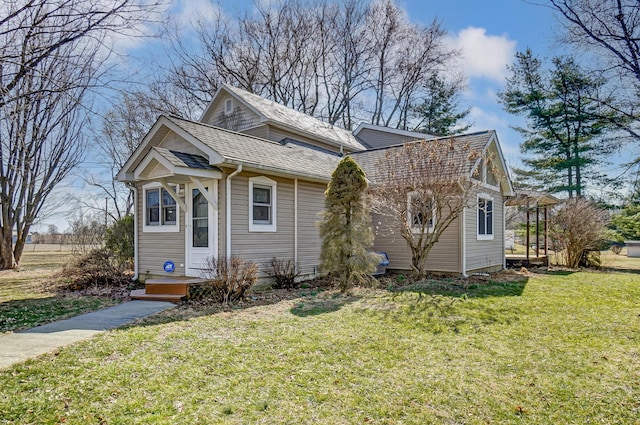 bungalow with a front yard and a shingled roof