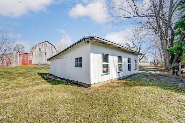 view of side of property featuring a barn, a lawn, and an outdoor structure